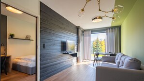 A modern living room with a sofa, a dining table, and a bed with a desk. - RentPlanet - Apartament Schroniskowa (Szklarska Poreba)