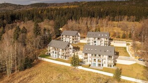 A residential complex with multiple two-story buildings, surrounded by a forested area. - RentPlanet - Apartament Schroniskowa (Szklarska Poreba)