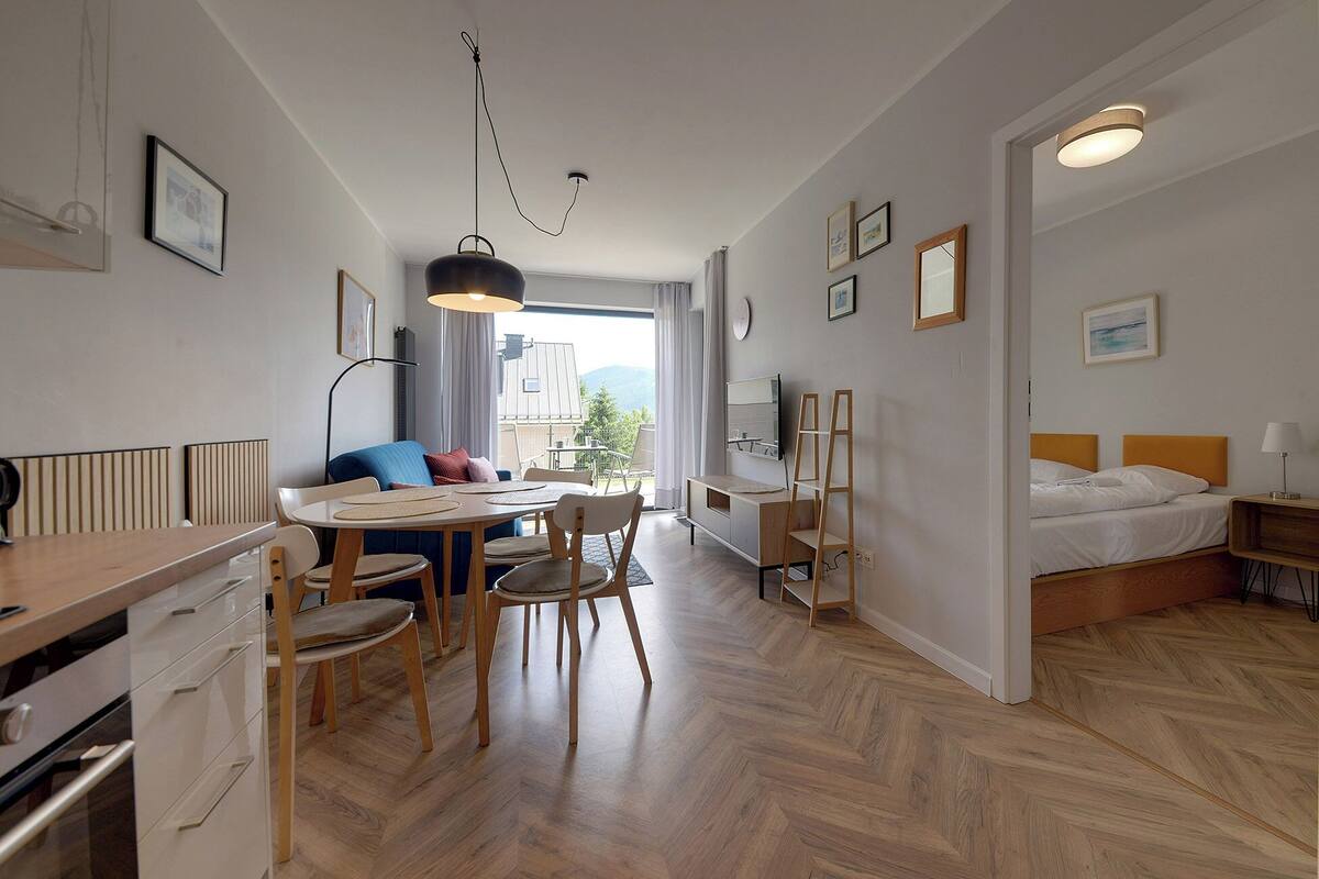A modern, well-lit room with a dining area, a bed, and a view of the outdoors.