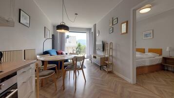 A modern, well-lit room with a dining area, a bed, and a view of the outdoors.