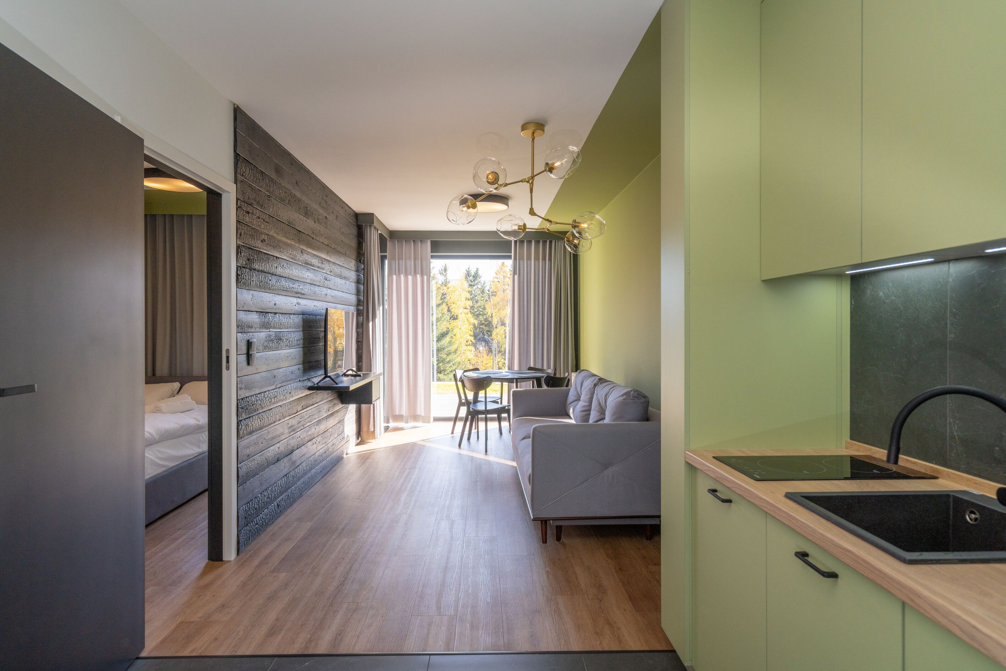 Een moderne keuken met een inbouwfornuis, een eethoek met een tafel en stoelen, en een bank.