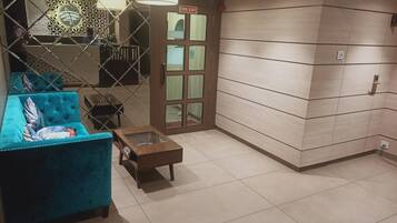 Un hall de hotel con un sofá azul, una pequeña mesa de madera y una puerta de salida de incendios.