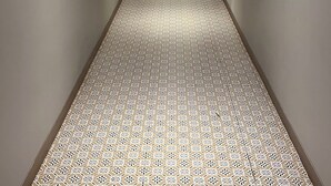 A long hallway with patterned carpet, framed artwork on the walls, and recessed lighting. - Rudra Shelter Business Hotel (Vasai)
