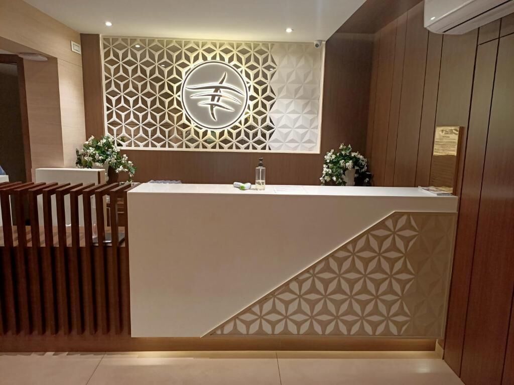 A reception desk with a geometric patterned wall, a wooden partition, and a small potted plant.