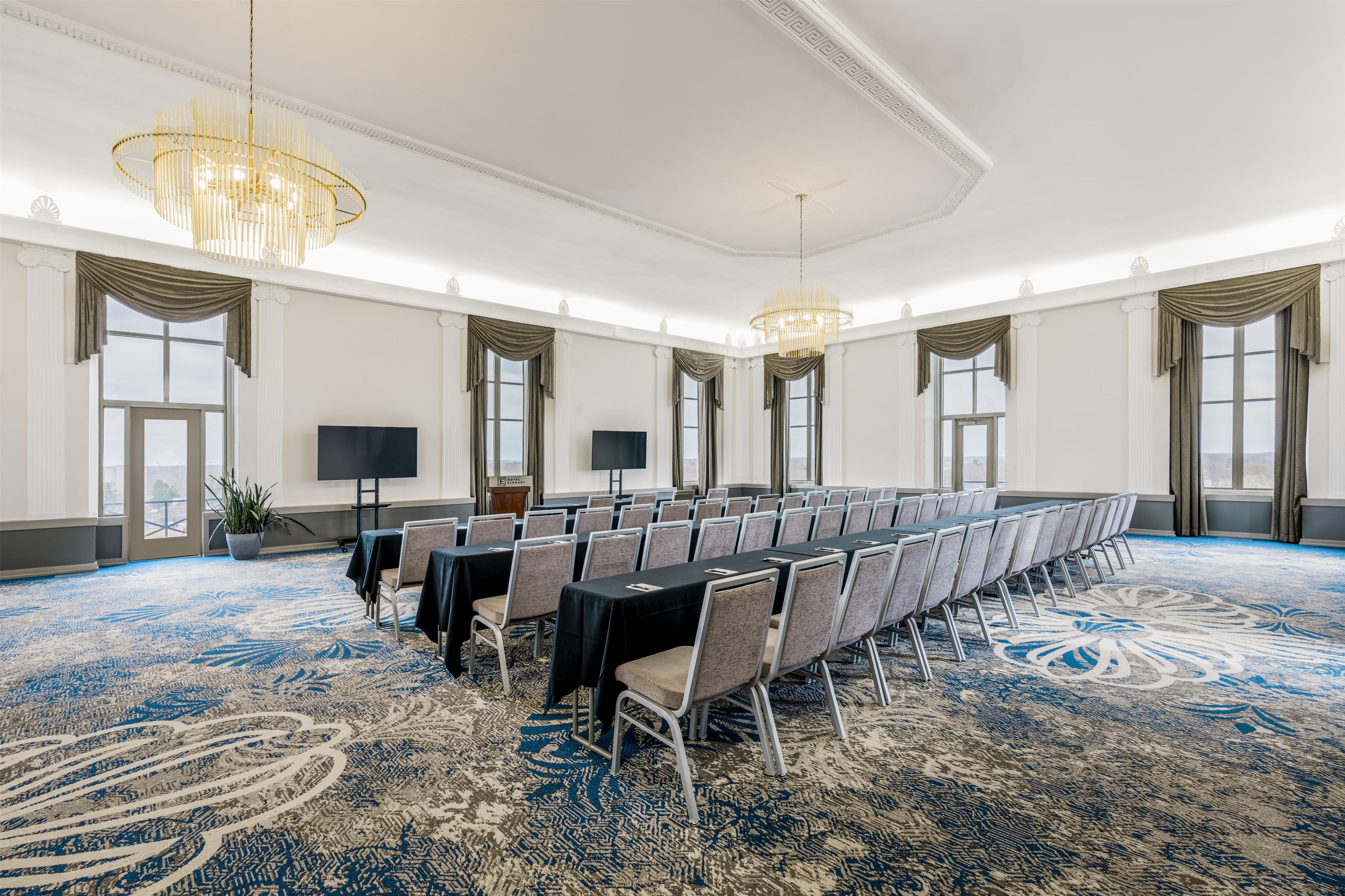 A conference room with a long table, chairs, a chandelier, and large windows.