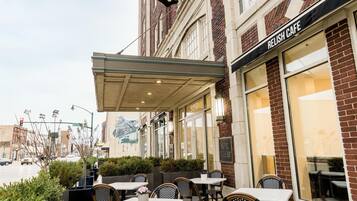 An outdoor seating area with tables and chairs, a building with a 'Hotel Elkhart' sign, and a 'Relish Cafe' across the street.