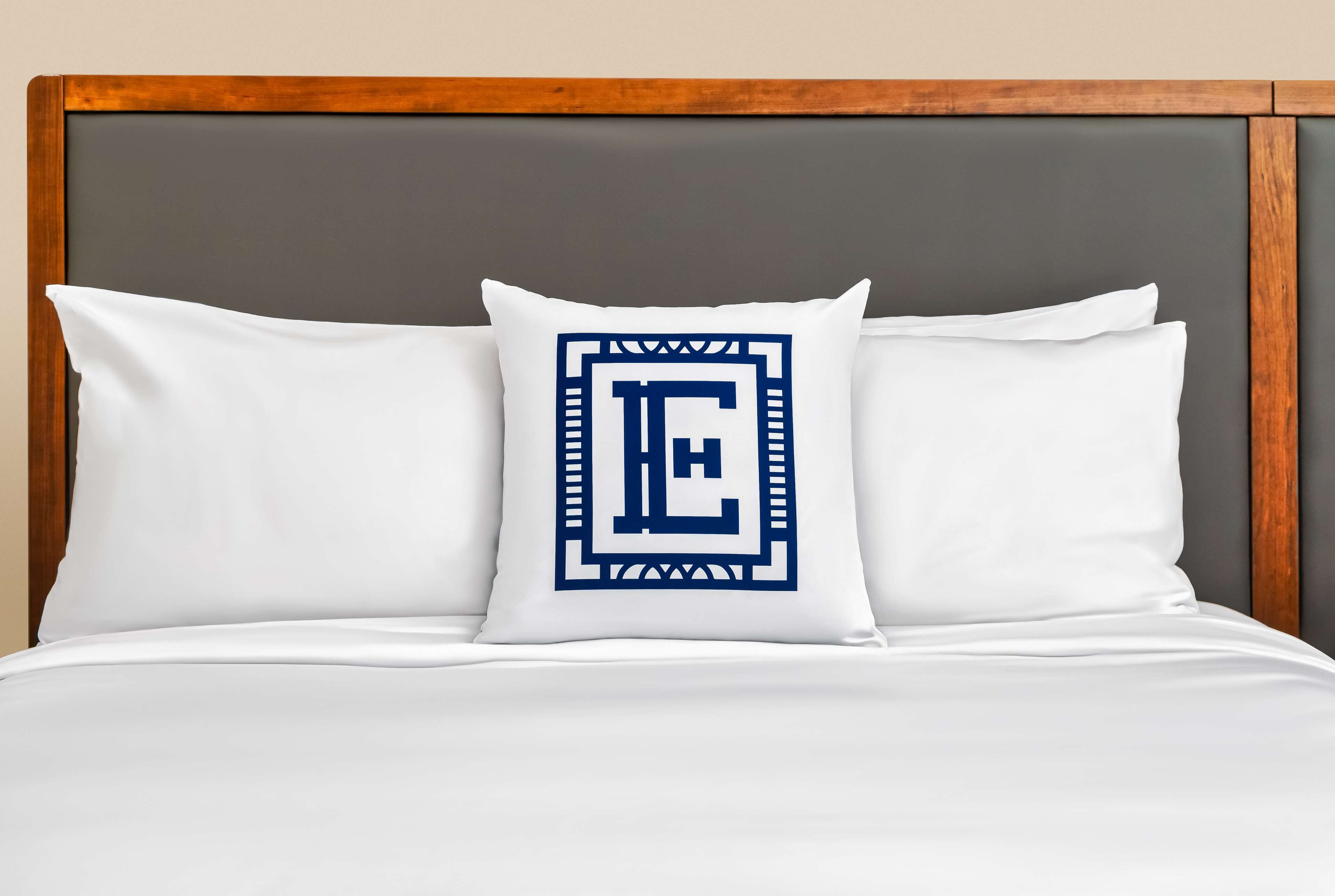 Una cama con ropa de cama blanca y una almohada decorativa con un diseño geométrico azul.