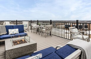 A deck with a fire pit, seating area, and a view of the cityscape.