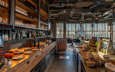 A modern kitchen with wooden shelves, a variety of glassware, and a buffet setup.