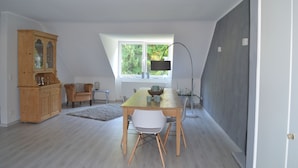 A dining area with a wooden table, chairs, a cabinet, and a window with a view of greenery. - 2.5 room apartment in central forest location Essen-Bredeney/Rüttenscheid (Essen)