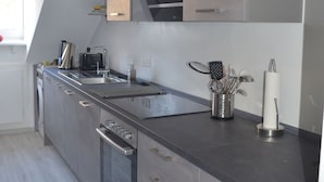 A modern kitchen with stainless steel appliances, a built-in oven, and a large island with a sink. - 2.5 room apartment in central forest location Essen-Bredeney/Rüttenscheid (Essen)