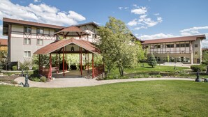 A building with a covered outdoor seating area, a lawn, and a pond.