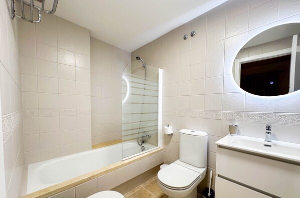 A modern bathroom with a bathtub, toilet, and sink.
