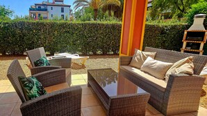 A patio area with wicker furniture, a glass coffee table, and a barbecue grill. - Apartment with garden & direct access to the pool CAP01 (Ayamonte)