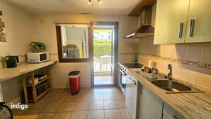 A compact kitchen with a microwave, sink, and cabinets. There's a trash bin and a window leading to a balcony. - Apartment with garden & direct access to the pool CAP01 (Ayamonte)