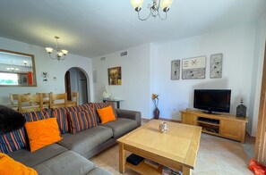 A living room with a sofa, coffee table, TV, and artwork on the wall. - Modern 3 Bedroom Duplex with Large Sunlit Terrace Southwest facing BIS02 (Ayamonte)