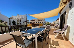 A terrace with a ping pong table, chairs, and a sunshade. - Modern 3 Bedroom Duplex with Large Sunlit Terrace Southwest facing BIS02 (Ayamonte)