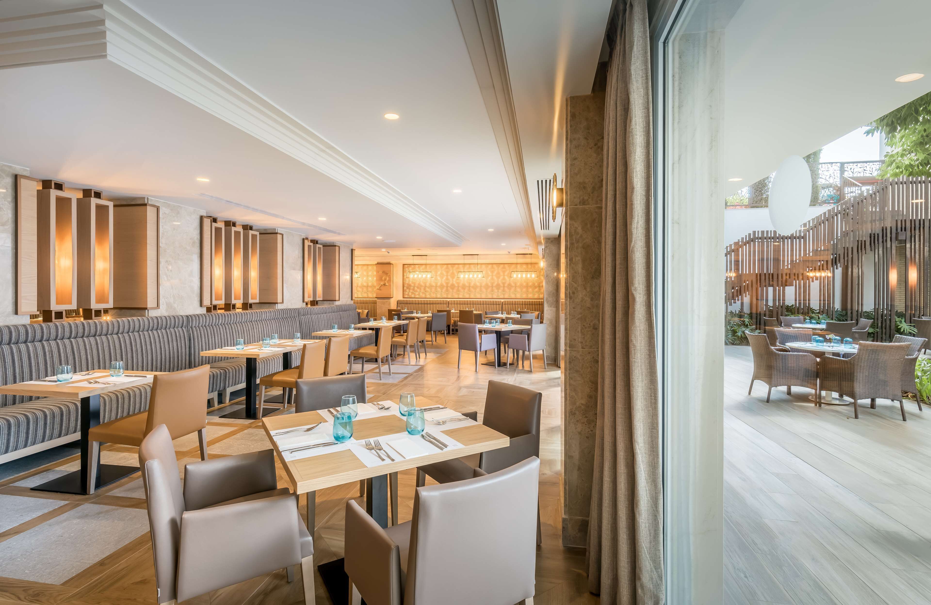 Ein modernes Restaurant mit verschiedenen Sitzgelegenheiten, darunter gemütliche Sitzecken, Tische und eine Bar.