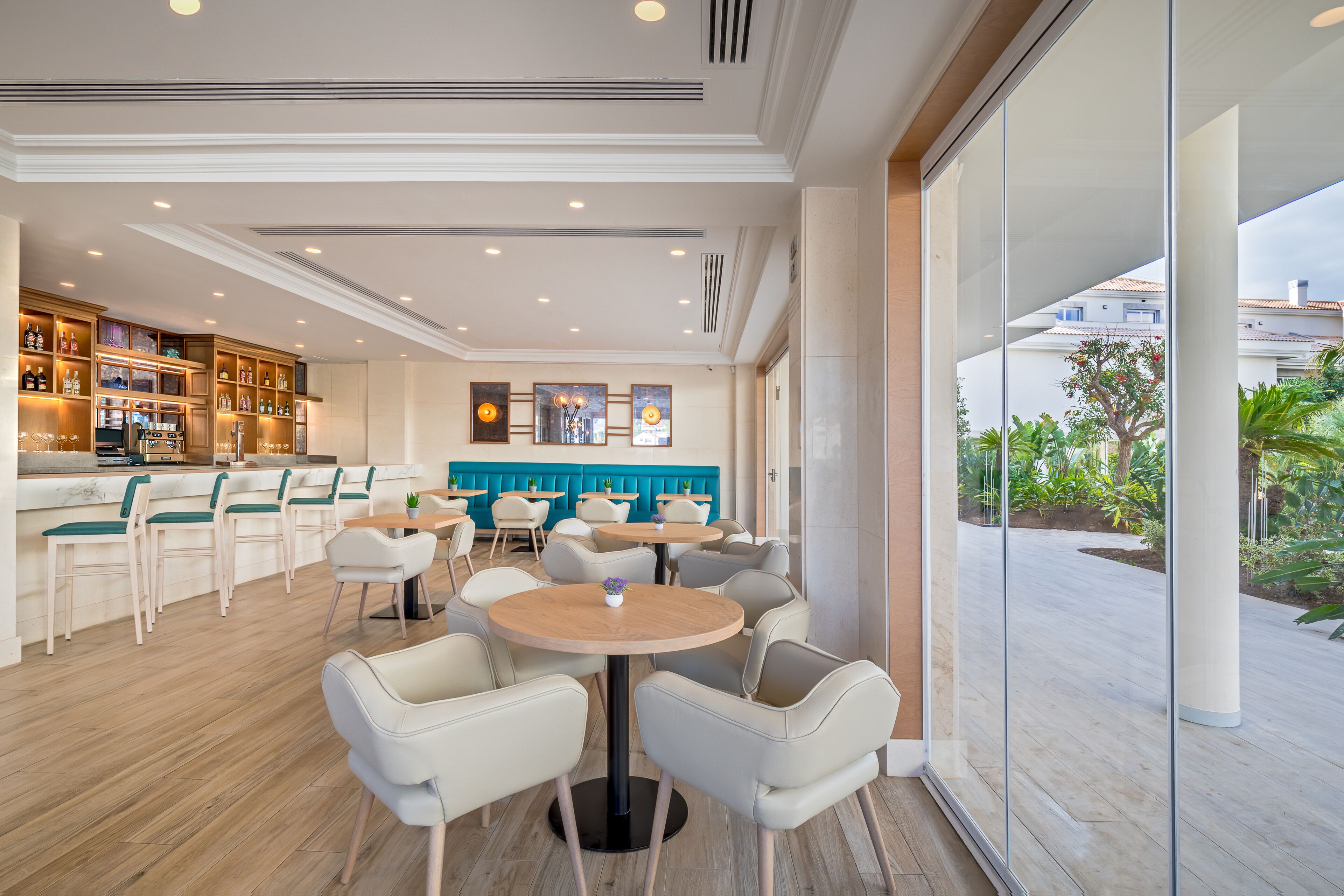 A modern bar area with seating, a kitchen, and a view of the outdoors.