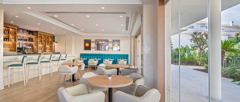 A modern bar area with seating, a kitchen, and a view of the outdoors.