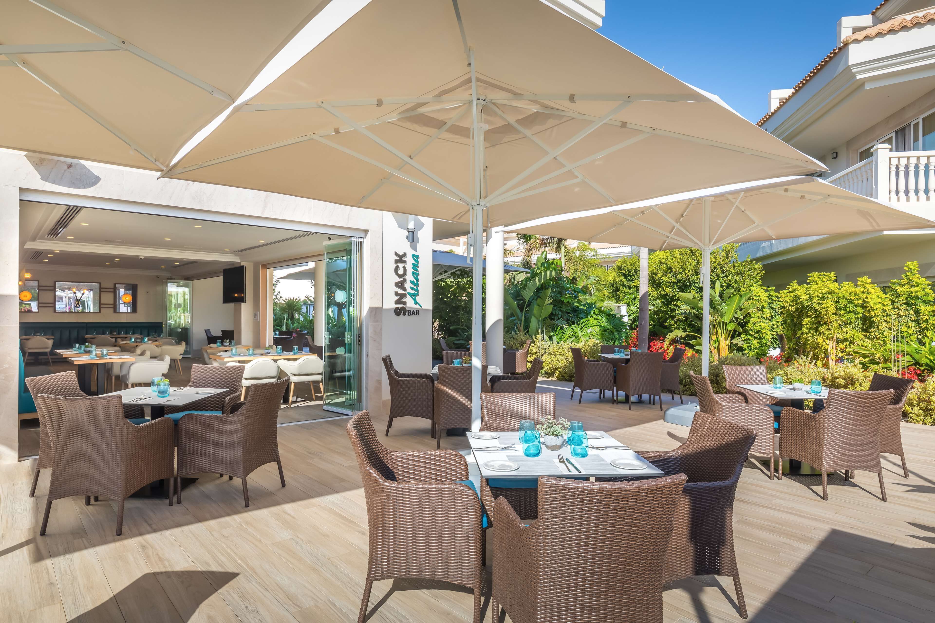 An outdoor dining area with wicker furniture and large umbrellas.