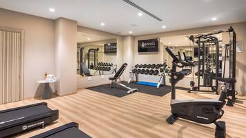 A modern gym with cardio equipment, weight machines, and dumbbells.