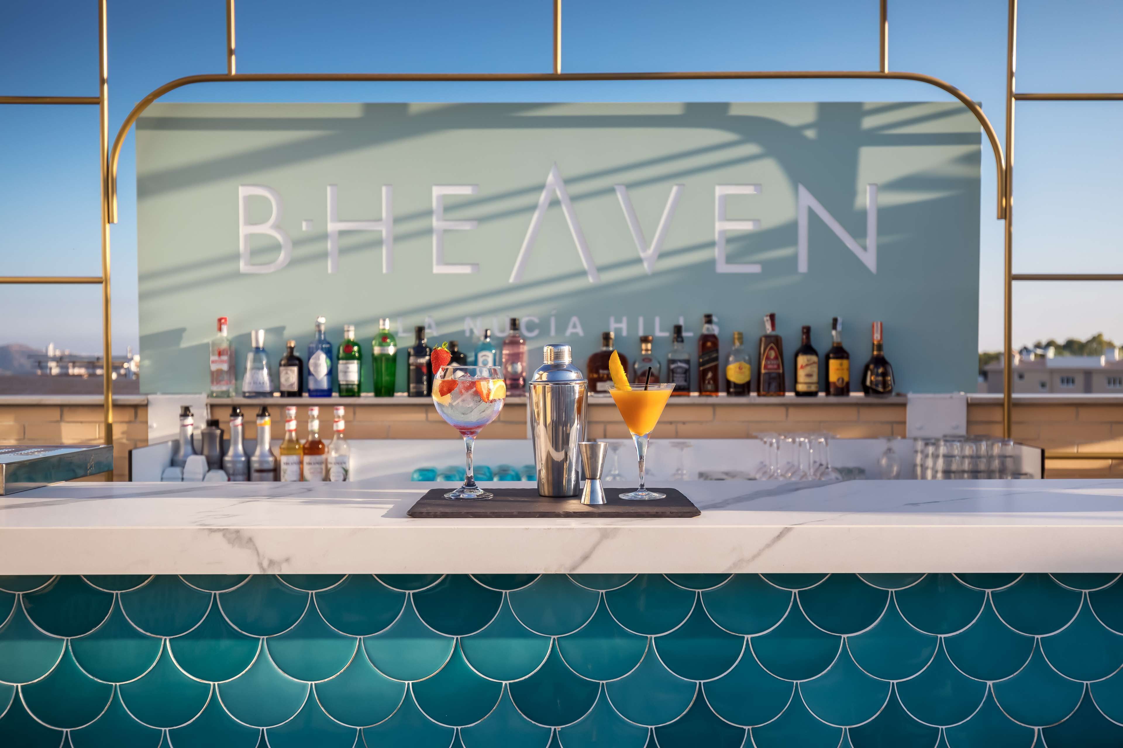 A bar area with a sign reading "B.HEAVEN" and a variety of bottles and drinks.