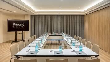 A conference room with a long table, chairs, a projector screen, and a wooden wall.