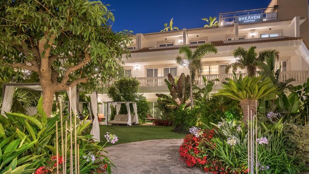 A hotel courtyard with a stone pathway, lush greenery, and a pergola. - Barcelo La Nucía Hills (La Nucia)