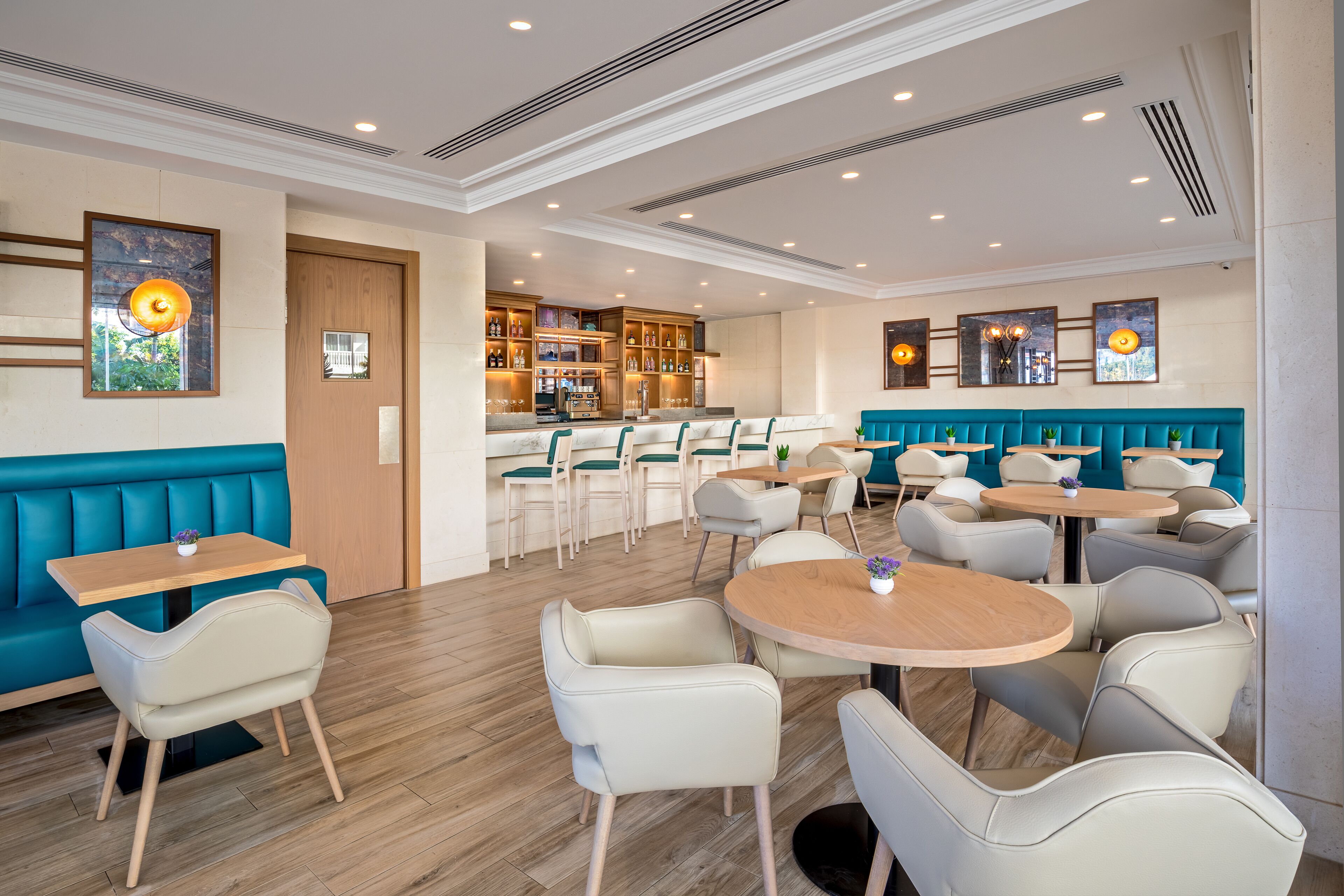A modern restaurant with booths, round tables, and a bar area.