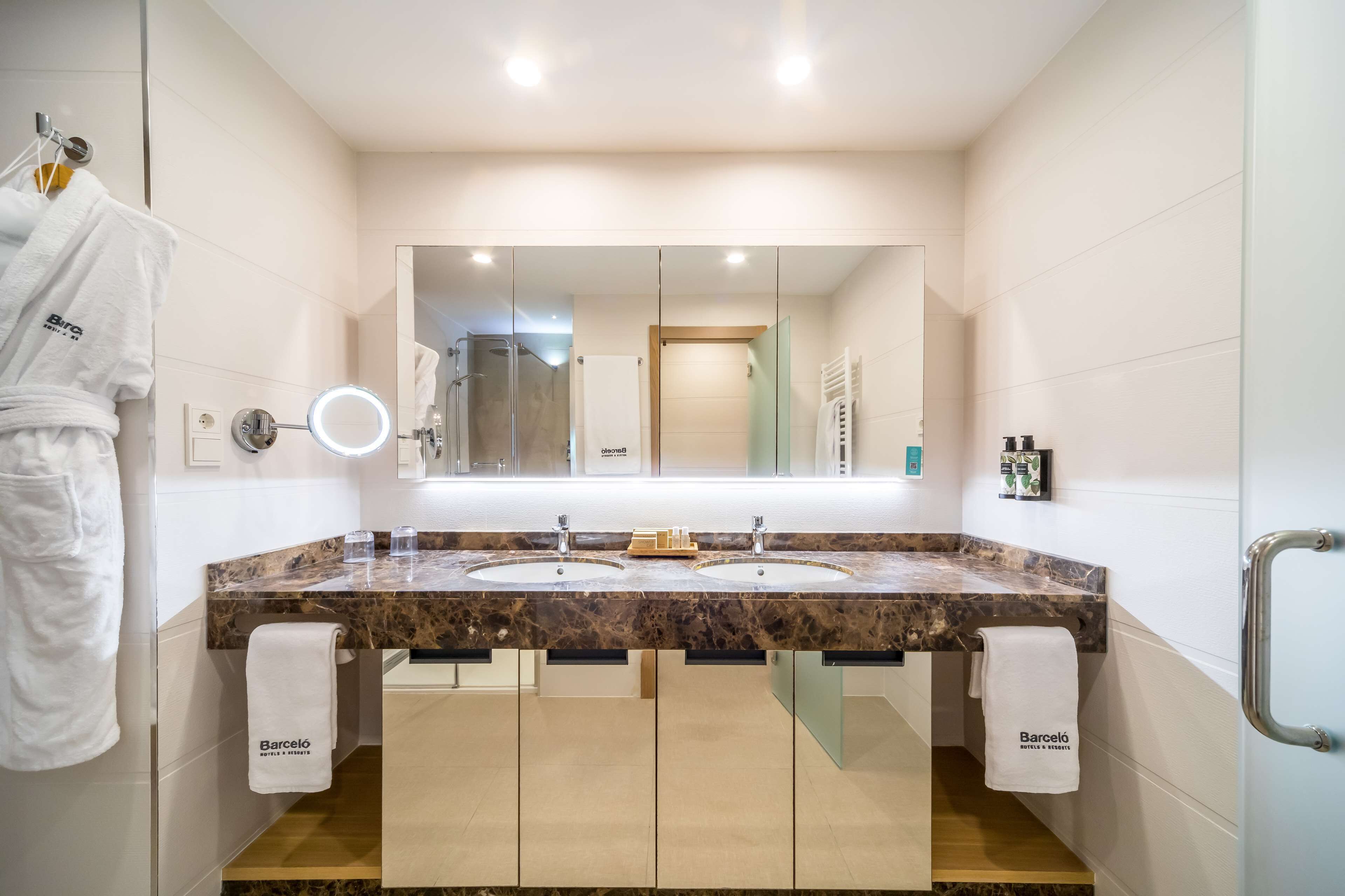 Un baño moderno con dos lavamanos, un espejo grande y una zona de ducha.