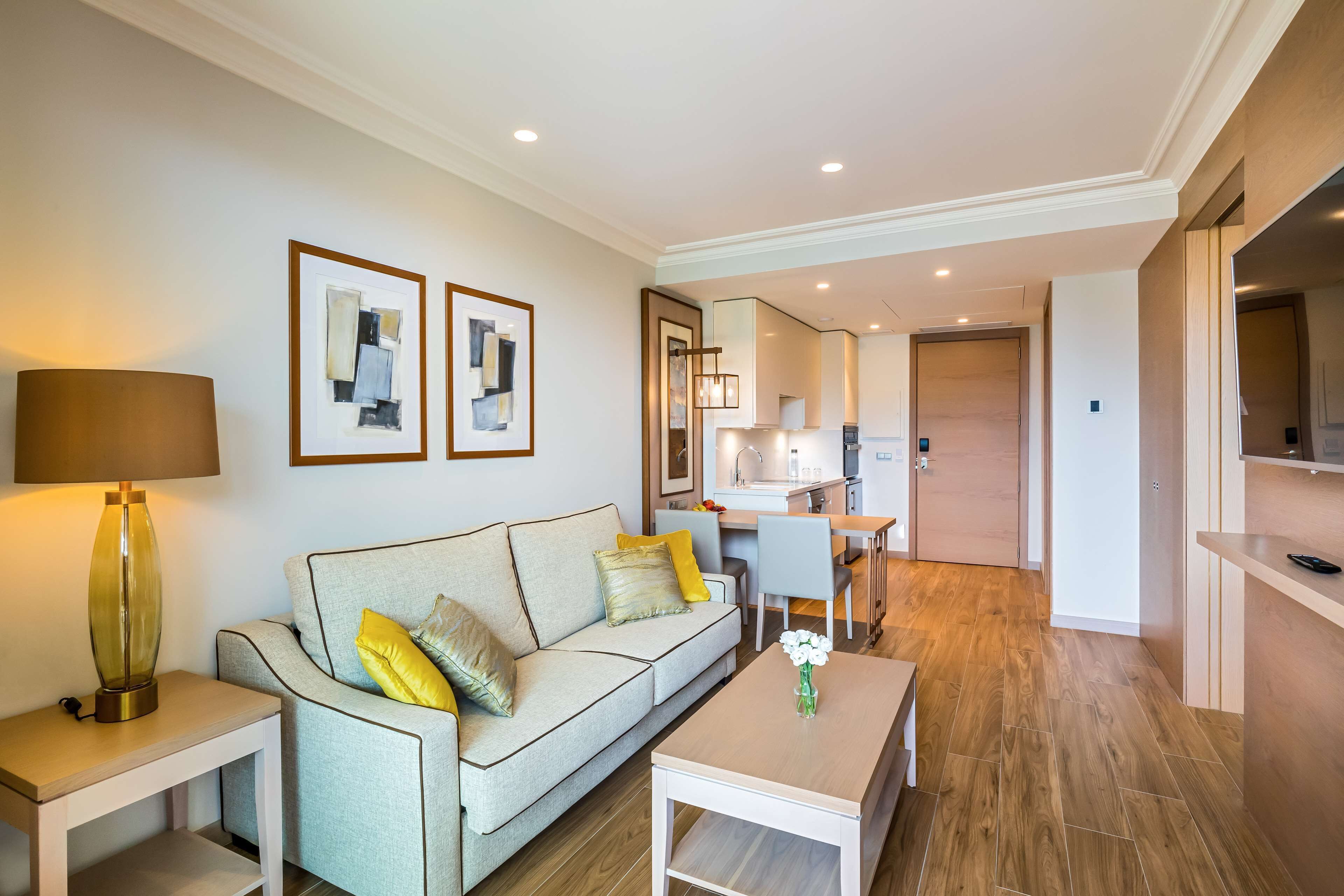 A modern living room with a sofa, coffee table, and a dining area.