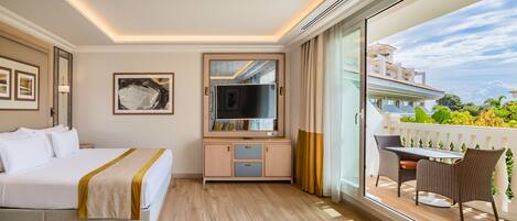 A hotel room with a bed, a TV, a balcony with a table and chairs, and a view of the outside.