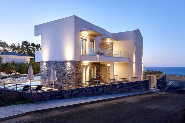 A modern two-story house with a stone facade, a balcony, and a view of the sea. - Theasea Stylish Residences (Mylopotamos)