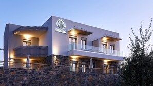 A modern hotel with a stone facade, multiple balconies, and a prominent logo. - Theasea Stylish Residences (Mylopotamos)
