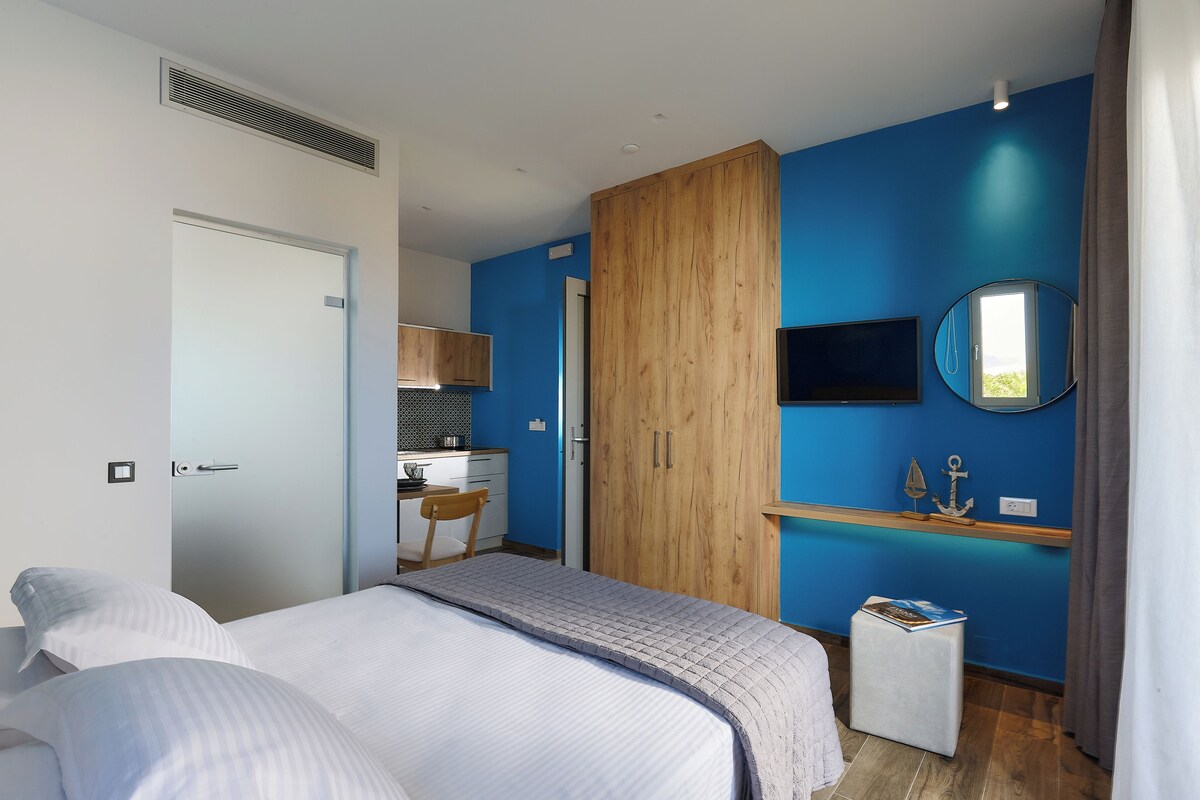 A bedroom with a bed, a desk, a wardrobe, and a mirror.