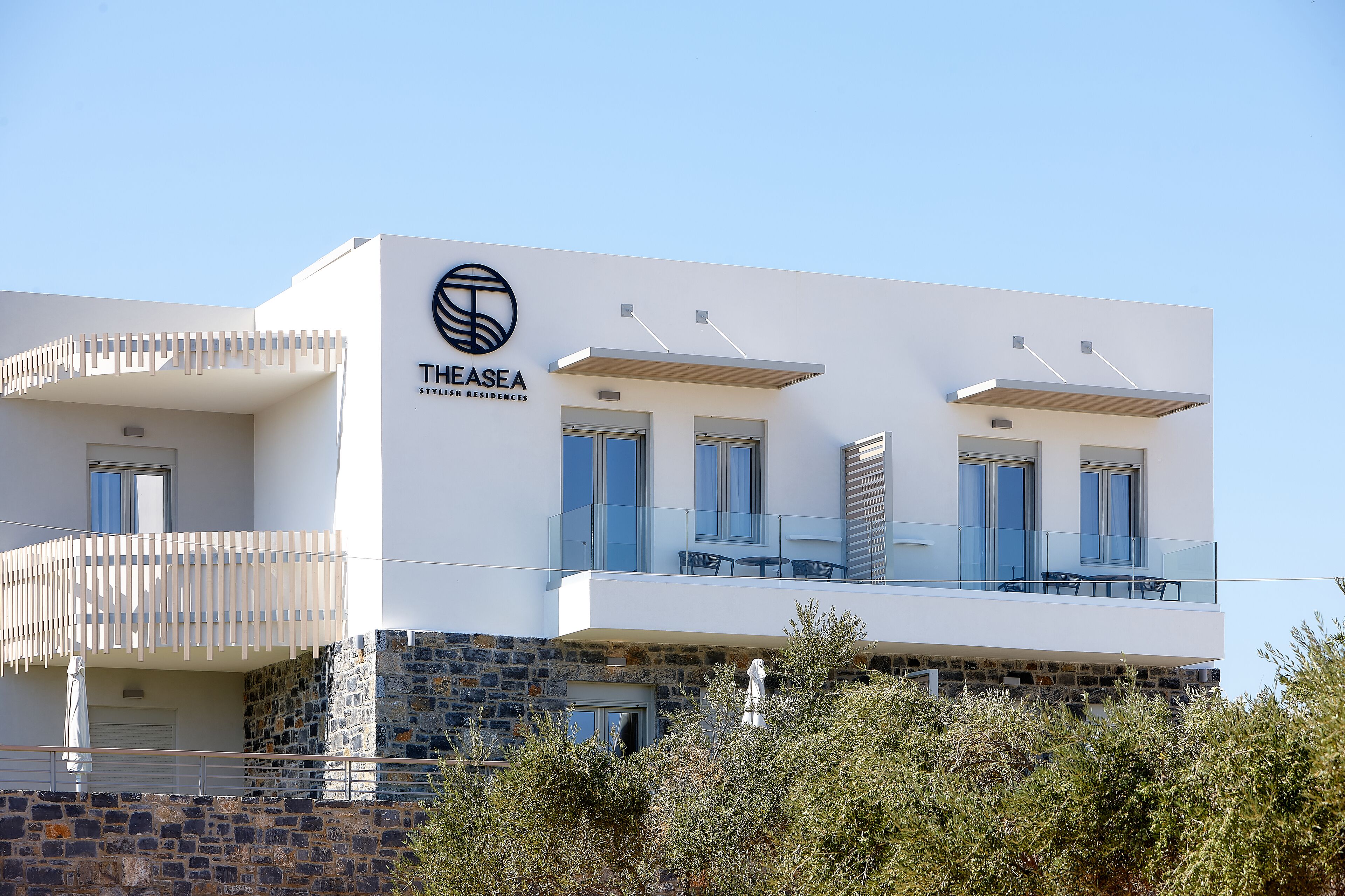 En moderne bygning med hvid facade, et logo og navnet "THESEA", der angiver et hotel eller resort.