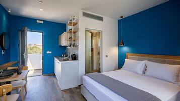 Habitación de hotel compacta con cama, kitchenette pequeño, zona de comedor y ducha.