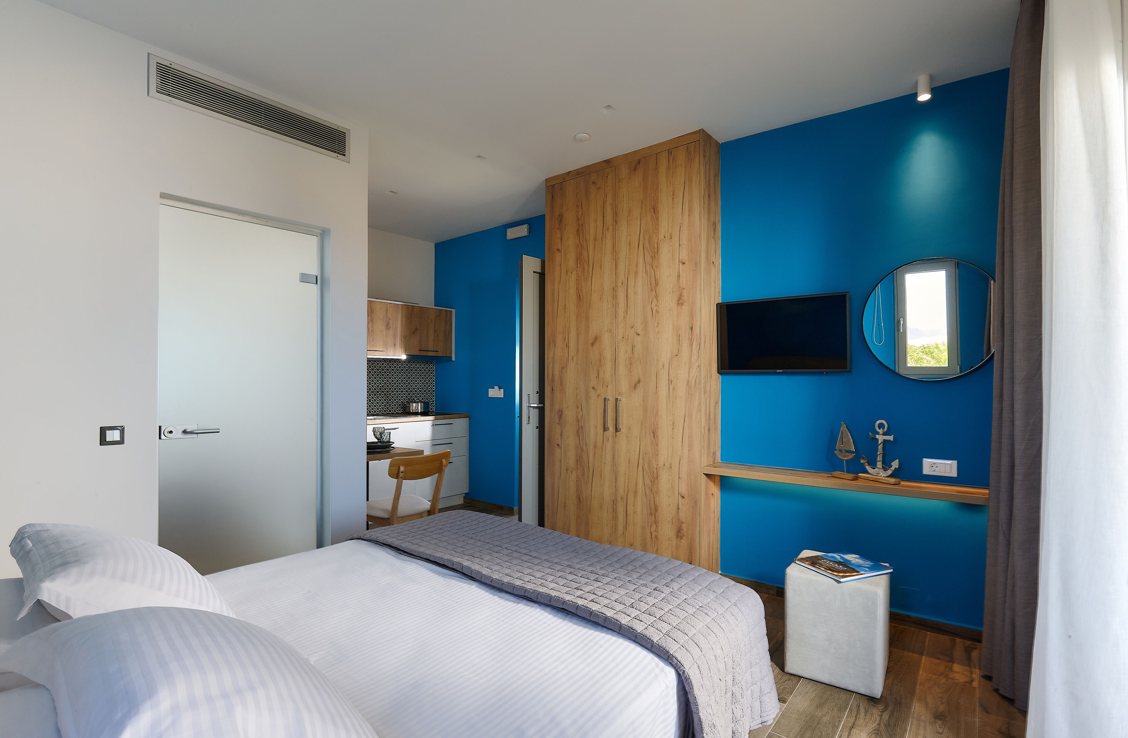 A bedroom with a bed, a desk, a wardrobe, and a mirror.