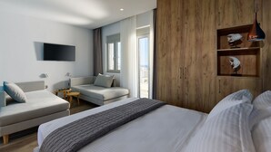 A modern hotel room with a large bed, a sofa, a TV, and a wooden wardrobe. - Theasea Stylish Residences (Mylopotamos)