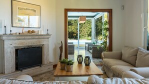 A living room with a fireplace, a sofa, a coffee table, and a view of the outdoors. - Luxurious Villa "Las Hortensias" with Private Pool, Garden & Wi-Fi (Santa Brígida)