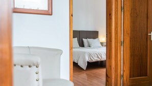 A room with a bed, a chair, and a wooden door. - Luxurious Villa "Las Hortensias" with Private Pool, Garden & Wi-Fi (Santa Brígida)