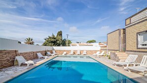 Ein Swimmingpool mit Liegestühlen und einer Steinmauer.