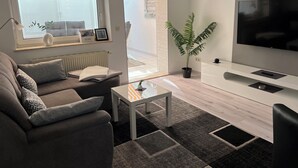 A modern living room with a sofa, coffee table, and a TV. - Ferienwohnung Weidenblick (Barth)