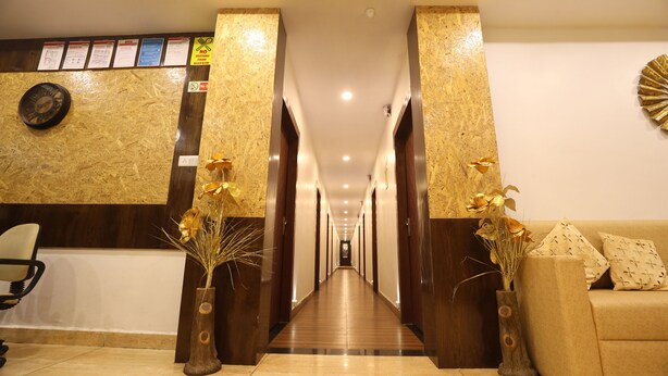 A hotel reception area with a wooden reception desk, a clock, and two vases with dried flowers. - Hotel Gaurishree (Bhopal)