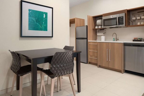 Una cocina moderna con comedor, que incluye un refrigerador, microondas y armarios de madera.