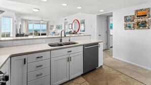 A modern kitchen with a large island, built-in cabinets, and a view to the outside.
