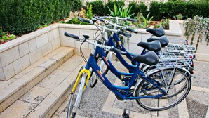 En blå cykel med en korg och en gul framgaffel står parkerad på en bänk av sten.