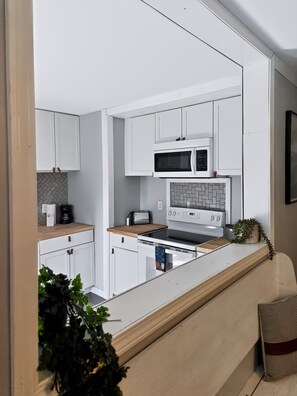 Une cuisine moderne avec des meubles blancs, un four à micro-ondes, une cuisinière et un grille-pain.