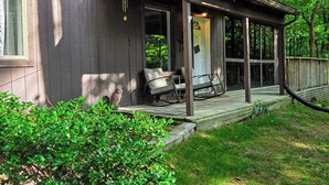 A wooden cabin with a porch, outdoor seating, and a covered area.
